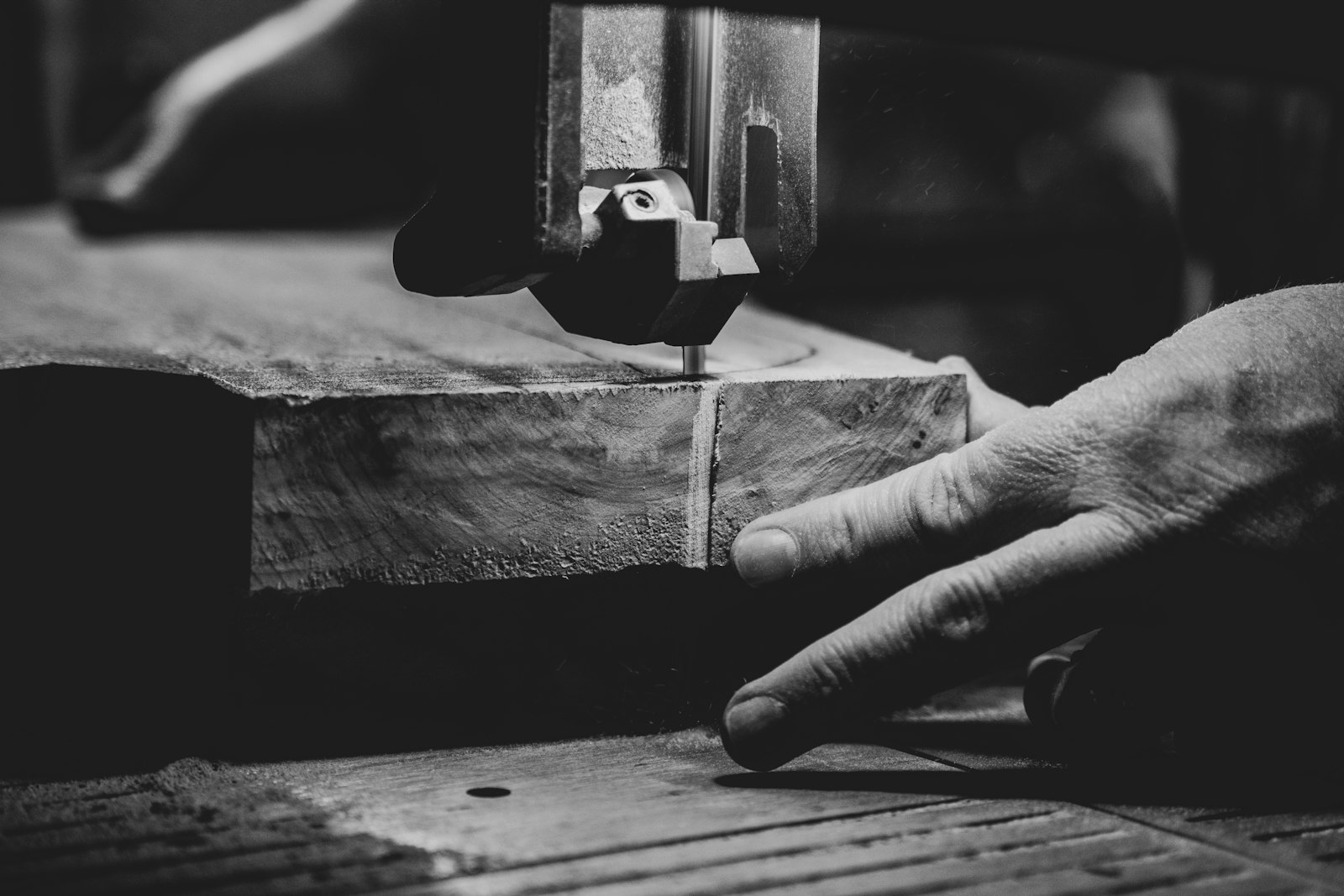 Handwerker führt ein Werkstück an der Bandsäge, Schwarz-Weiß-Aufnahme